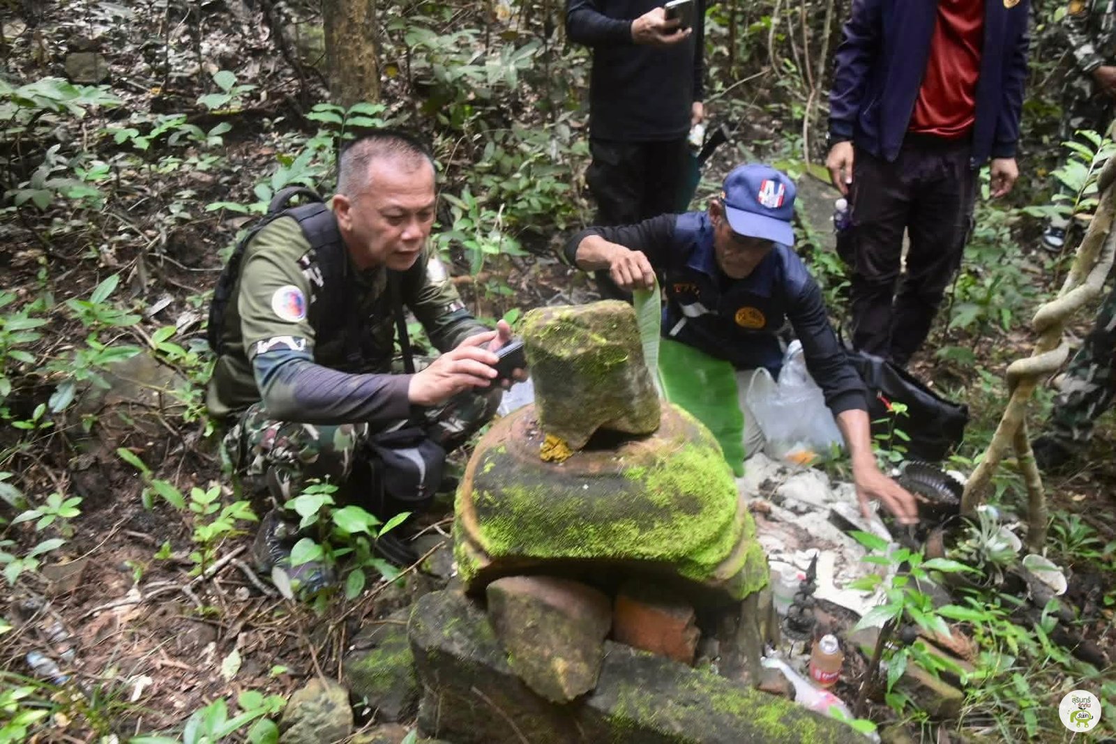 ผู้ลงพื้นที่สังเกตชิ้นส่วนหินที่มีมอสปกคลุม ภาพจากชุดที่ต้นทางนำมาเผยแพร่ประกอบเรื่องปราสาทดินแดง